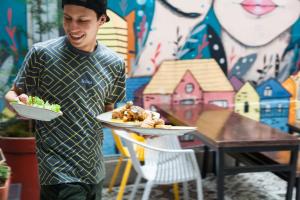 a man holding two plates of food on a table at Socialtel Candelaria Bogotá in Bogotá