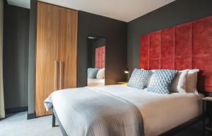a bedroom with a large bed with a red headboard at The Gate London City in London