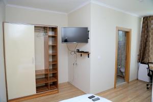 Zimmer mit einem TV an der Wand und einem Bett in der Unterkunft Troy Lodge in Lusaka