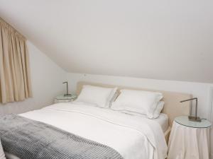 a white bedroom with a white bed with two lamps at St Julien in Dawlish