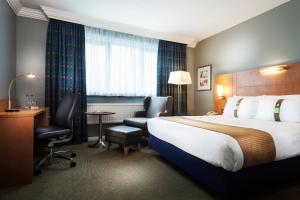 a hotel room with a bed and a desk and chair at Holiday Inn London Bloomsbury, an IHG Hotel in London