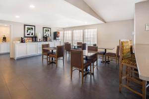 a dining room with tables and chairs and a kitchen at La Quinta Inn by Wyndham Caldwell in Caldwell