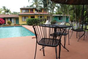 eine Gruppe Stühle und ein Tisch neben einem Pool in der Unterkunft Hotel Bristol Aeropuerto in Alajuela