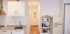 uma cozinha com armários brancos e um frigorífico branco em Apartamento acogedor a 3 minutos de la playa em Blanes