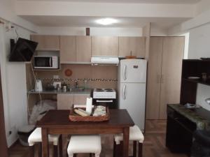 a small kitchen with a table and a white refrigerator at Seliuqanan in Ushuaia