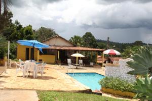 una casa con piscina con sillas y sombrillas en Pousada Cachoeirinha, en Baependi