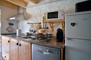 a kitchen with a sink and a white refrigerator at REFÚGIO DO RAPOSO/CASA DENEB (CC) in Montes da Senhora