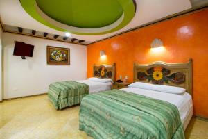 2 camas en una habitación con paredes de color naranja en Suites Flamboyanes, en Mérida