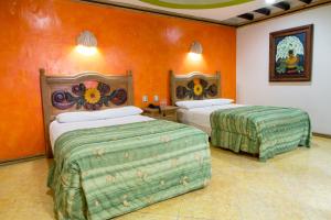 two beds in a room with orange walls at Suites Flamboyanes in Mérida