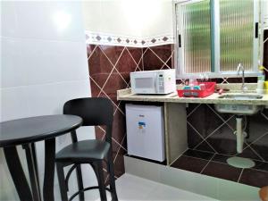 a small kitchen with a table and a microwave at Pousada Casa Verde - Curitiba in Curitiba