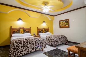 a hotel room with two beds and a ceiling at Suites Flamboyanes in Mérida