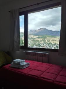 1 dormitorio con cama roja y vistas a la montaña en Altos de Esquel en Esquel