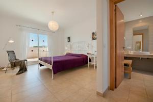 1 dormitorio con cama morada y baño en Villa Marisa I, en Alcudia