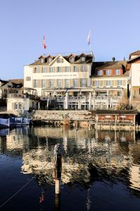 a building with a boat in the water in front at Hotel Hirschen am See in Meilen