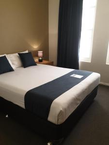 a large bed in a bedroom with a window at Adelaide Pulteney Motel in Adelaide