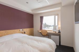 ein Hotelzimmer mit einem Bett, einem Schreibtisch und einem Fenster in der Unterkunft Nikko Station Hotel 2 in Nikko