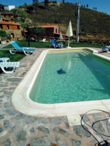 einen Pool in einem Resort mit Stühlen und einem Tisch in der Unterkunft REFÚGIO DO RAPOSO/CASA DENEB (CC) in Montes da Senhora