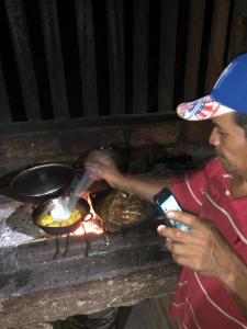 Een man bereidt eten boven een open grill. bij Hostal La Gloria in Mérida