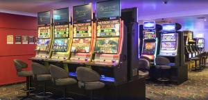 une rangée de machines à sous dans une pièce avec des chaises dans l'établissement Albatross Bay Resort, à Weipa