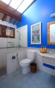 uma casa de banho com um WC e uma parede azul em Rumah Ganesha Ubud em Ubud