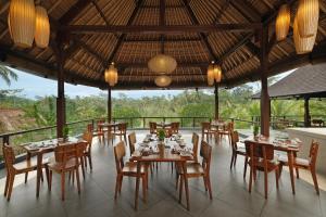 a restaurant with tables and chairs and a view of the forest at Puri Sebali Resort in Ubud