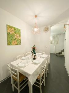 una sala da pranzo bianca con tavolo e sedie bianchi di OROROSA Lucca City Center Apartment a Lucca