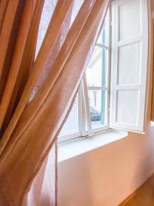 a window with a curtain on a window sill at OROROSA Lucca City Center Apartment in Lucca