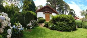uma pequena casa num jardim com flores e arbustos em Chalés Monte Verde em Monte Verde
