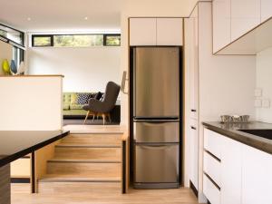 a kitchen with a stainless steel refrigerator next to a staircase at The Treehouse - Kaiteriteri Holiday Home in Kaiteriteri