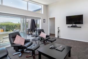 een woonkamer met stoelen en een flatscreen-tv bij Easy Days Martinborough in Martinborough 