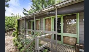 Cozy Stay Cottage في ديلسفورد: الشرفة الأمامية لبيت به نوافذ خضراء