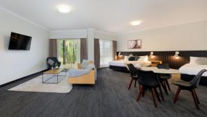 Habitación de hotel con 2 camas y sala de estar. en Parklands Resort, en Mudgee
