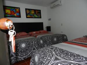 a bedroom with two beds with black and white sheets at Hotel Sucre Del Bosque in Palmira