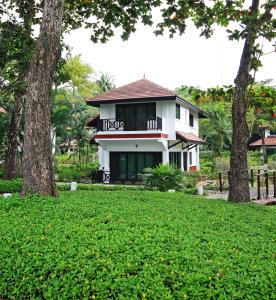 a white house with a balcony and two trees at Banyu Biru Villa in Lagoi