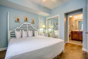 a bedroom with a large white bed and a bathroom at Seychelles Beach Resort IV in Panama City Beach