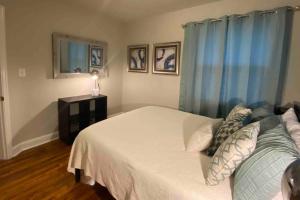 a bedroom with a white bed and blue curtains at Darling Cottage in University Park in Raleigh