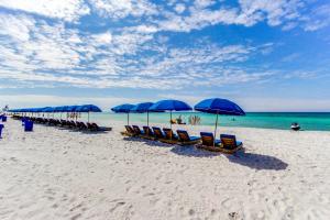 a row of blue umbrellas and chairs on a beach at Sunrise Beach Resort V in Panama City Beach