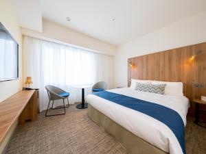 Habitación de hotel con cama grande y escritorio. en Tokyu Stay Okinawa Naha, en Naha