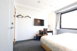 a bedroom with a bed and a desk and a tv at Hiroshima Town Hotel in Hiroshima