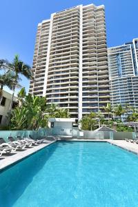 a swimming pool with chairs and a large building at Surfers Century Oceanside Apartments in Gold Coast