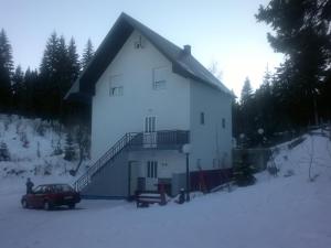 een wit huis met een auto in de sneeuw bij Guest House Kavedžić in Žabljak