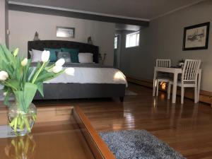 a bedroom with a bed and a table with a vase of flowers at Great Slave Lakeside Bed & Breakfast in Yellowknife