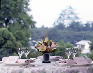 una mesa con platos y vasos y un jarrón de flores en KKR Hotel Nagoya en Nagoya