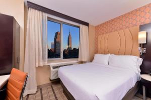 um quarto de hotel com uma cama grande e uma janela em Holiday Inn New York City - Times Square, an IHG Hotel em Nova Iorque