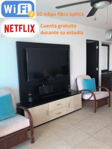 sala de estar con 2 sillas y TV grande en Torre Oceanica en Salinas - Ecuador, en Salinas