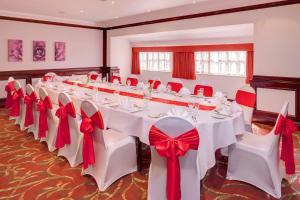 a banquet room with white tables with red bows at Holiday Inn Ipswich Orwell, an IHG Hotel in Ipswich