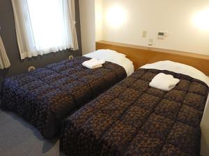 two beds in a hotel room with towels on them at Residence Hotel Will Shinjuku in Tokyo