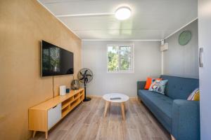 ein Wohnzimmer mit einem blauen Sofa und einem Tisch in der Unterkunft Cosy cabin to stay even better than Glamping in Pukekohe East