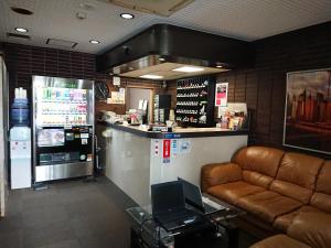 東京にあるレジデンス ホテル ウィル 新宿のカウチと冷蔵庫付きのバーのあるレストランを提供しています。