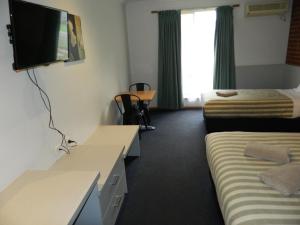 a hotel room with two beds and a flat screen tv at Werribee Motel and Apartments in Werribee